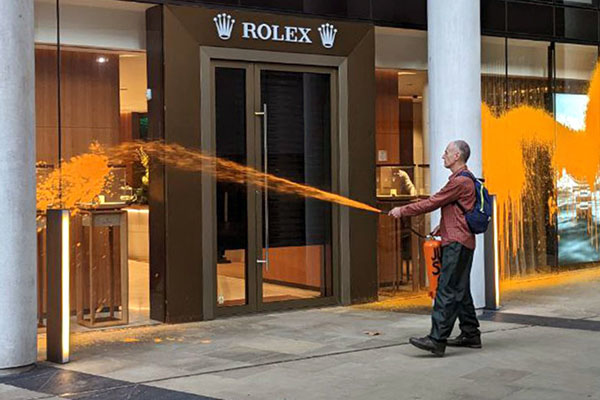 Ecologistas rocían pintura naranja en la fachada de una tienda de Rolex en Londres