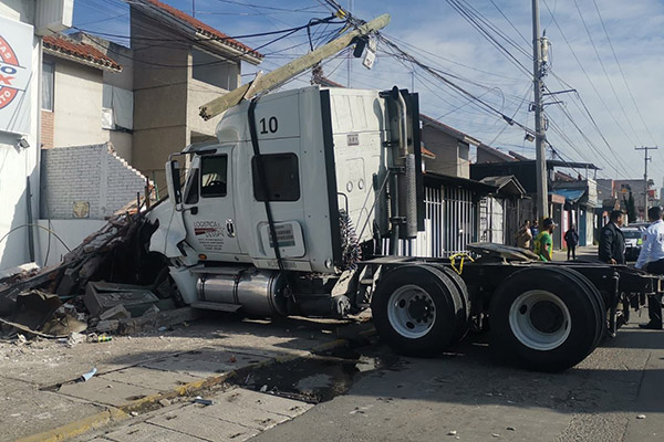Tractocamión impacta y derriba barda sobre una pareja
